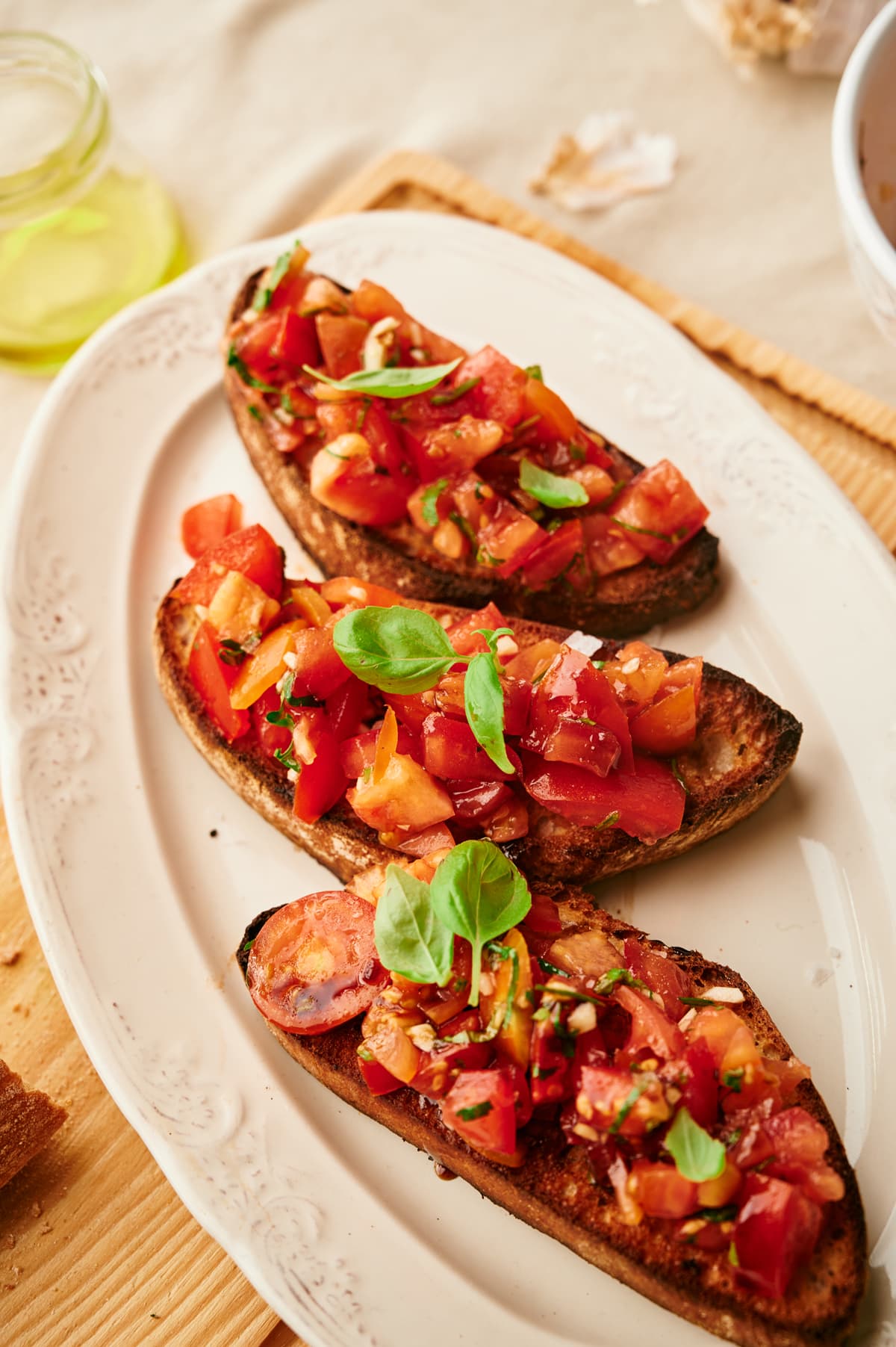three pieces of toasted bread with diced fresh tomatoes, olive oil and garlic on top, on a serving plate