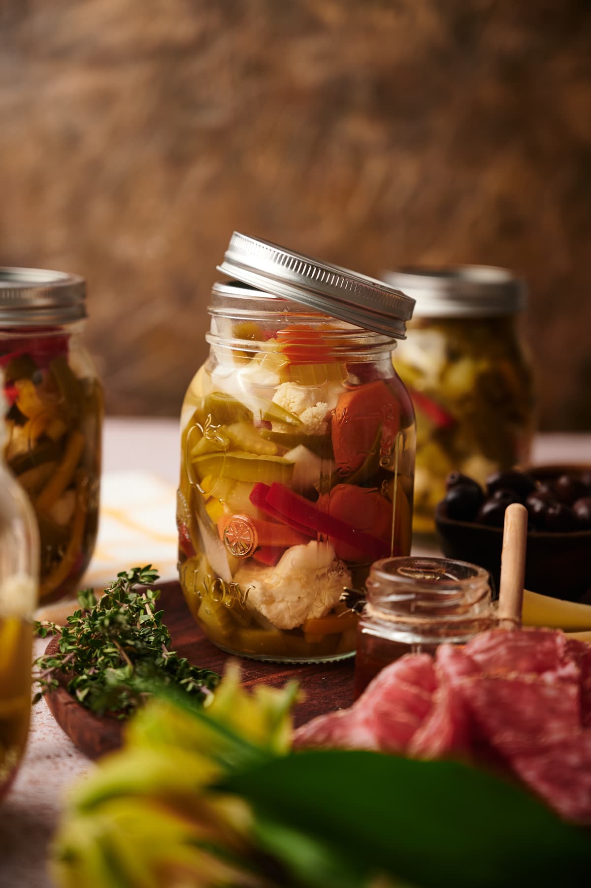 picture of homemade giardiniera in its vase on table with other appetizers
