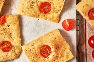 sliced tomato focaccia on a sheet pan with parchment paper