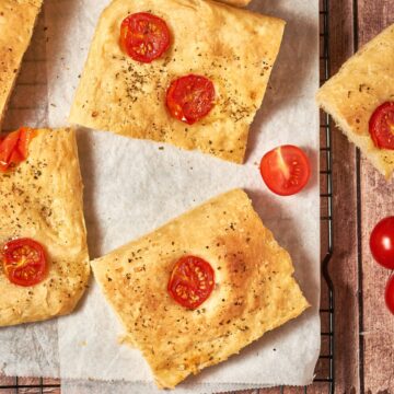 sliced tomato focaccia on a sheet pan with parchment paper