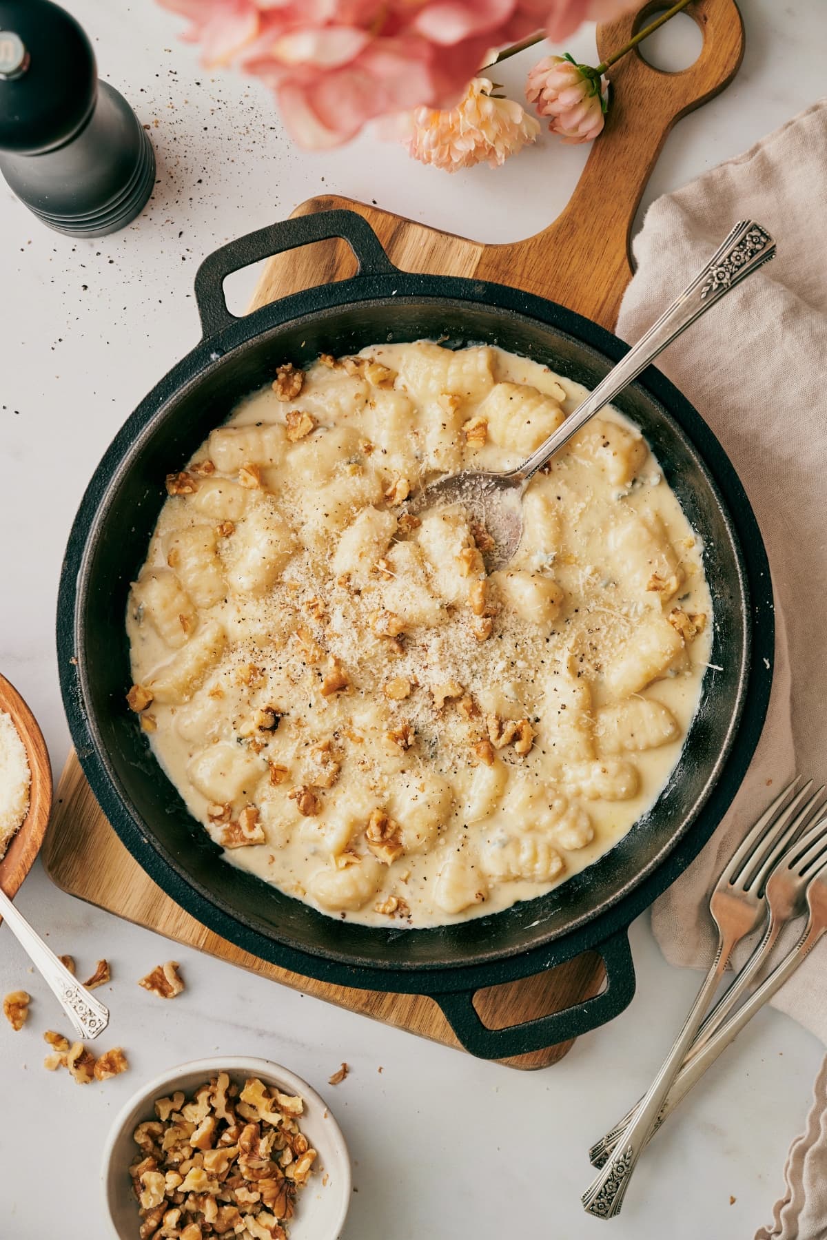 gnocchi with gorgonzola on a skillet with a spoon on top of a wooden chopping board