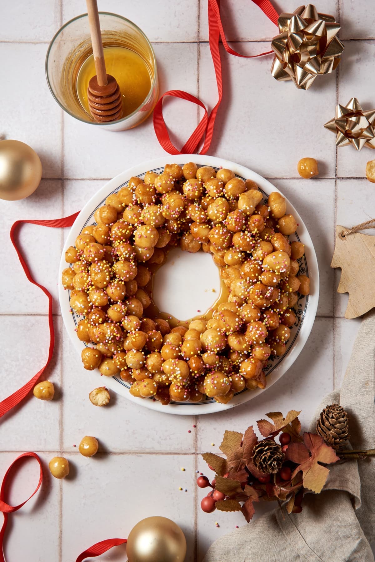 struffoli on a plate with Christmas ornaments surrounding the plate
