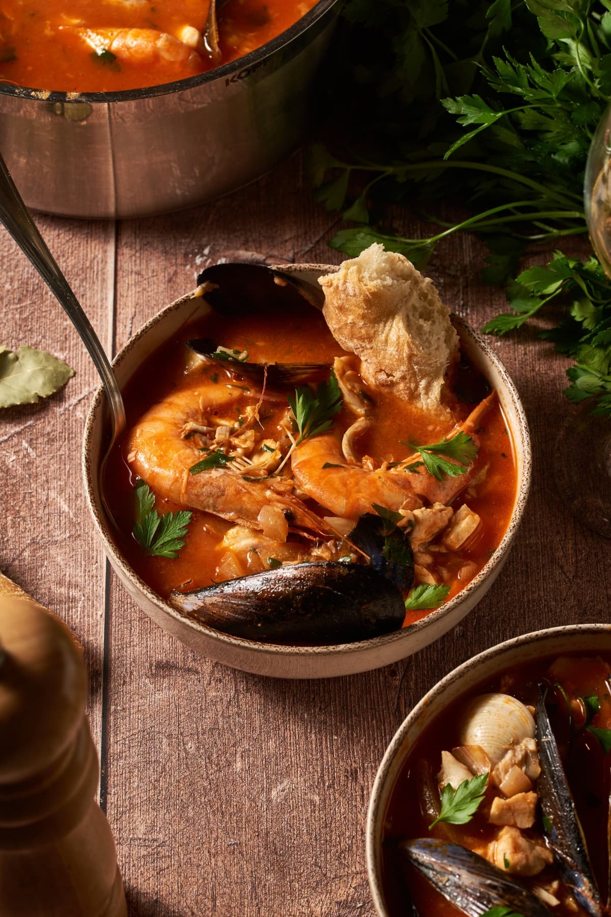 Bowl of seafood cioppino soup on a table with a piece of bread in it.