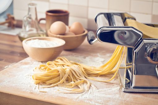 homemade fresh pasta and pasta machine on kitchen table